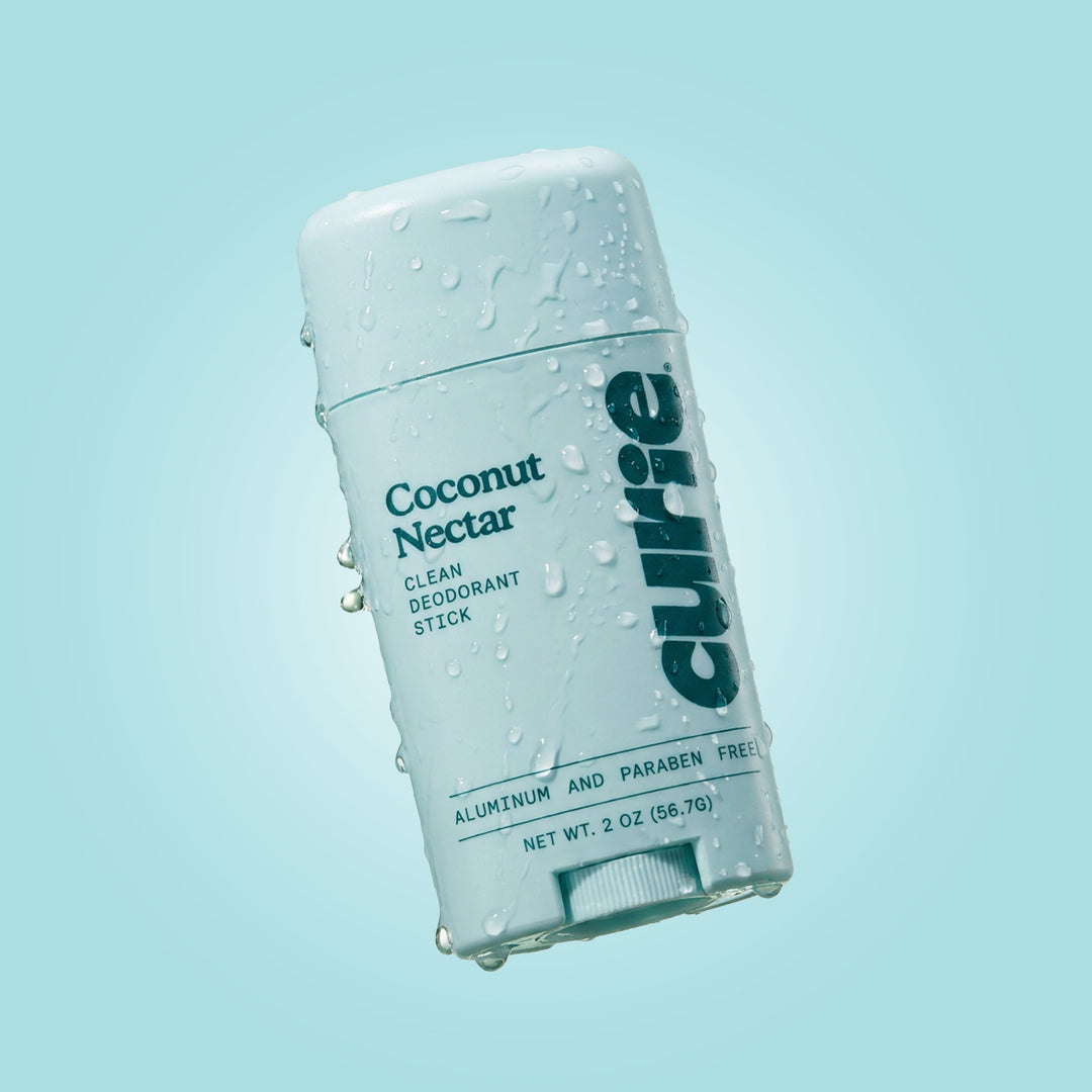 Curie Coconut Nectar Clean Deodorant Stick in a white plastic container with water droplets, set against a light blue gradient background.